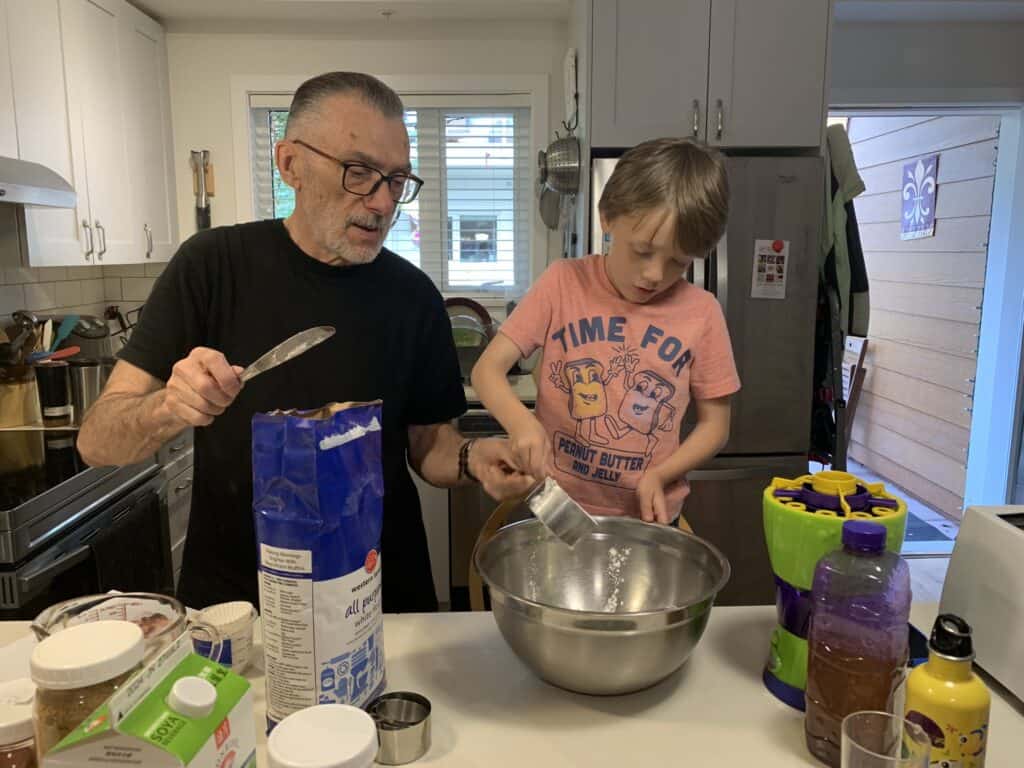 Elder and child baking in kitchen together.