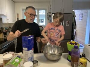 Elder and child baking in kitchen together.